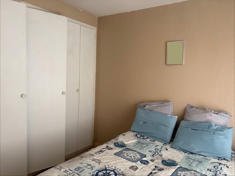 A bedroom featuring a built-in wardrobe with white doors and neutral wall finishes.