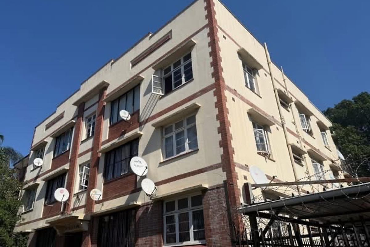 Exterior view of a multi-story apartment building featuring brick and plaster facade detailing and multiple window units.