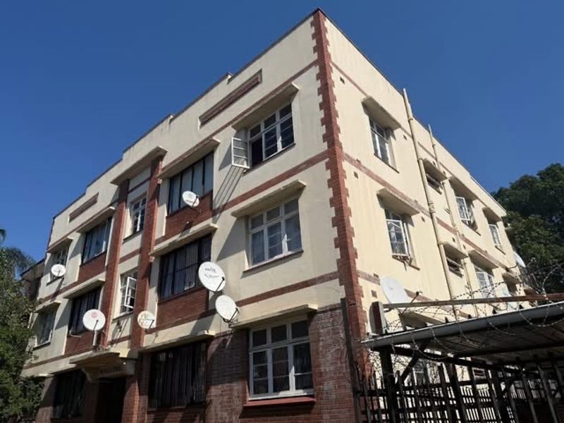 Exterior view of a multi-story apartment building featuring brick and plaster facade detailing and multiple window units.