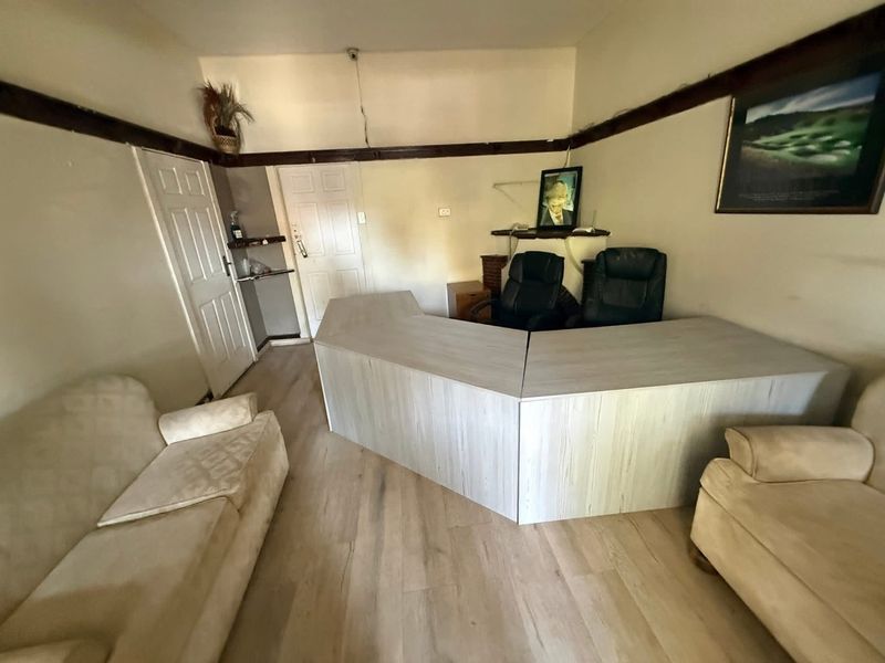 A functional office space featuring wood-look laminate flooring and a built-in reception-style desk unit.