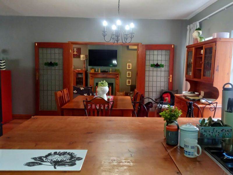 Open plan kitchen and dining area featuring a central island, gas cooktop, and traditional stained glass double doors leading to a fireplace lounge.
