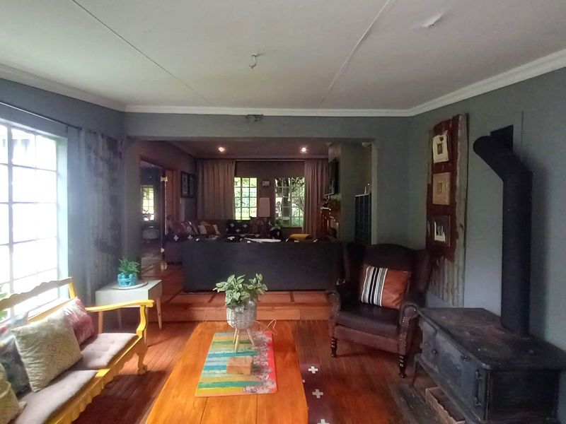 Spacious living room featuring hardwood flooring, a freestanding fireplace, and large windows that provide ample natural light and a view of the garden.
