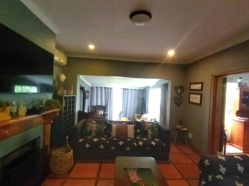 A cozy living room featuring a fireplace with a wooden mantelpiece, terracotta floor tiles, and an integrated split-system air conditioner.