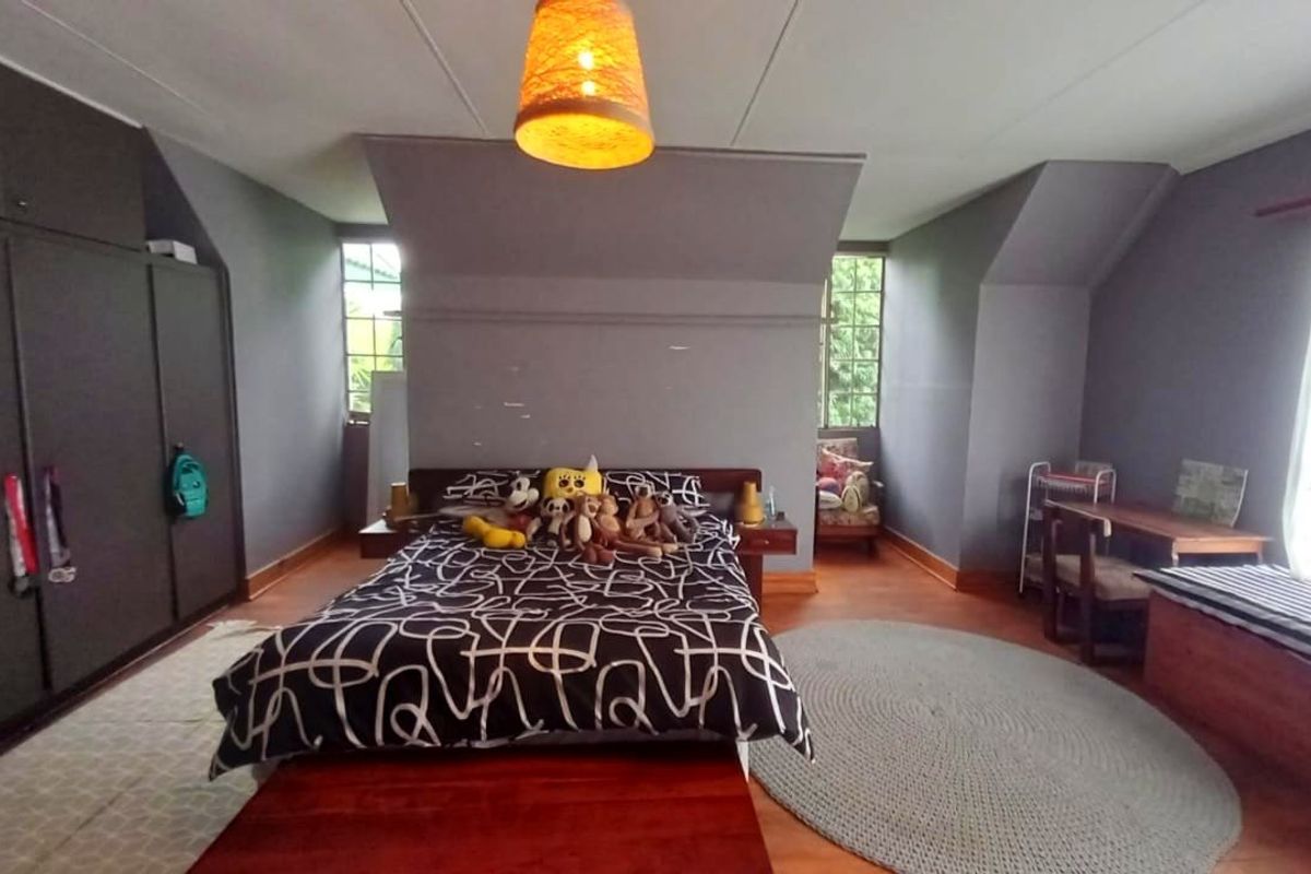Spacious bedroom featuring timber flooring, built-in cupboards, and dual aspect windows providing natural light.