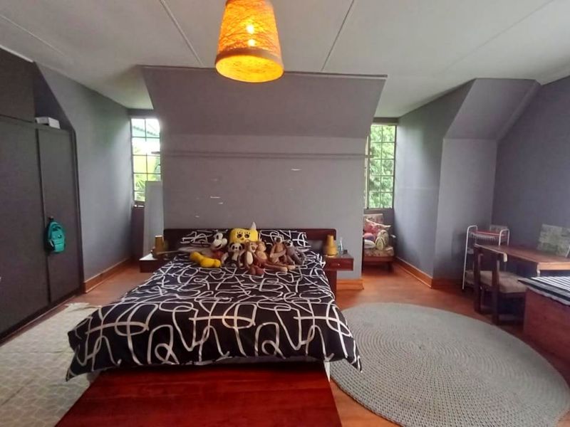 Spacious bedroom featuring timber flooring, built-in cupboards, and dual aspect windows providing natural light.