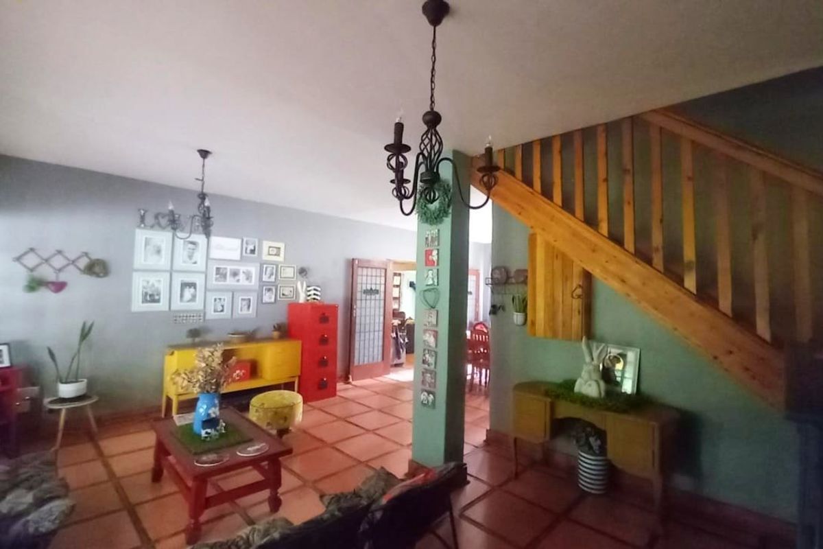 Spacious living area featuring terracotta floor tiles, a timber staircase, and traditional wrought iron lighting fixtures.