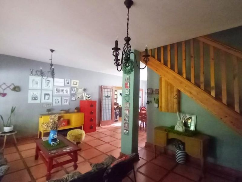Spacious living area featuring terracotta floor tiles, a timber staircase, and traditional wrought iron lighting fixtures.