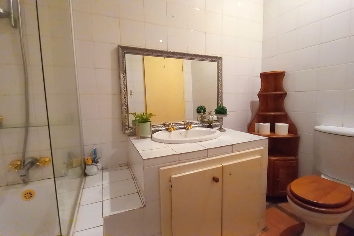 A functional bathroom featuring a shower enclosure, vanity cabinet with basin, and toilet, finished with white wall tiles.