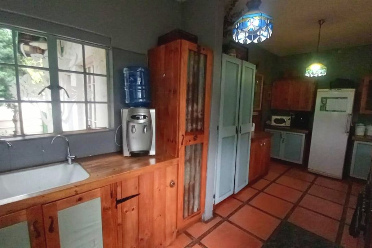 A rustic kitchen featuring wooden cabinetry, a ceramic sink, and terracotta-style tiled flooring, offering a traditional and functional workspace.
