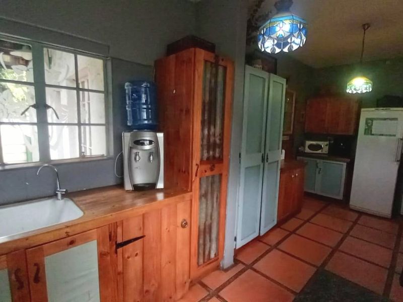 A rustic kitchen featuring wooden cabinetry, a ceramic sink, and terracotta-style tiled flooring, offering a traditional and functional workspace.