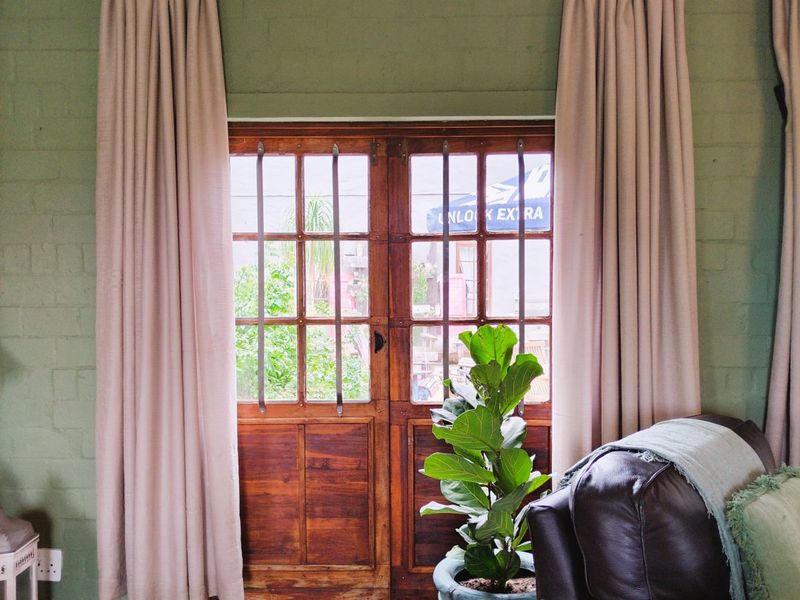 Living room featuring exposed timber ceiling beams, painted brick walls, and classic timber french doors leading to the exterior.