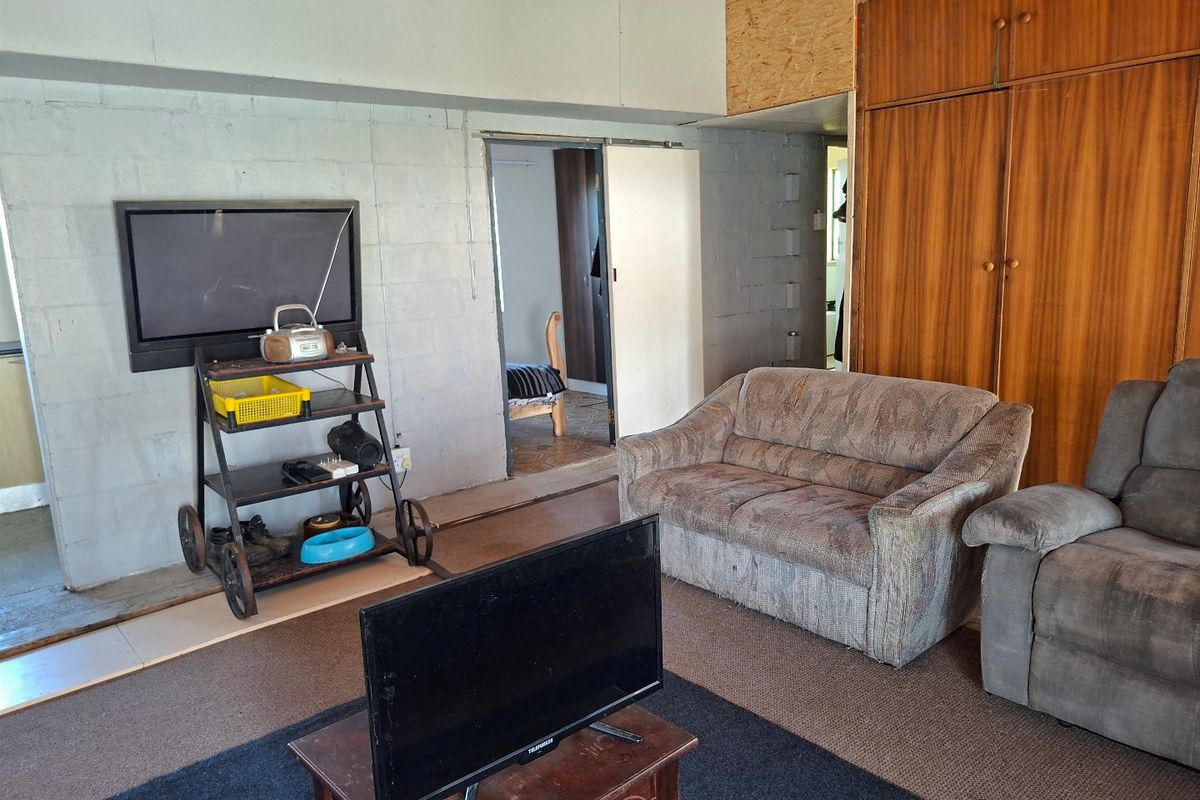 A living area featuring exposed blockwork walls, built-in wooden cabinetry, and a sliding door leading to an adjacent room.