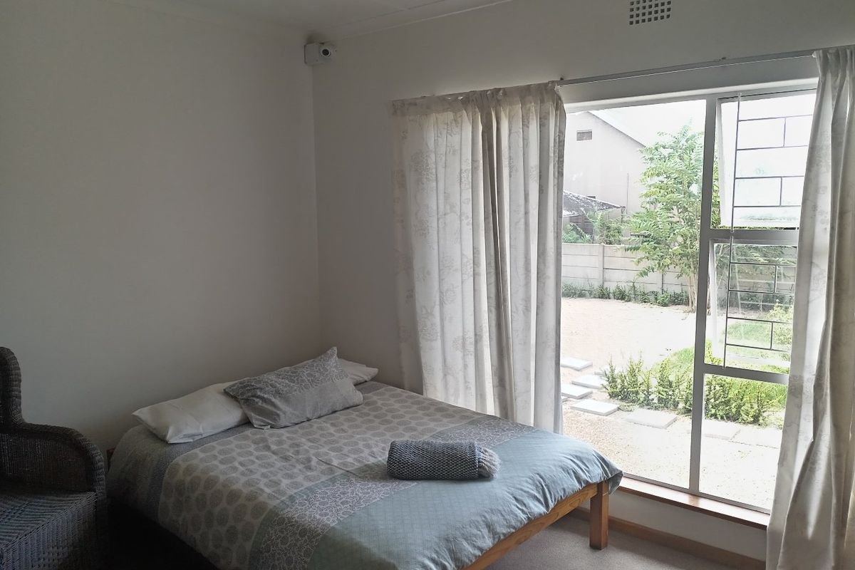 A bedroom featuring a sliding glass door with security gate, providing direct access to the rear garden area.