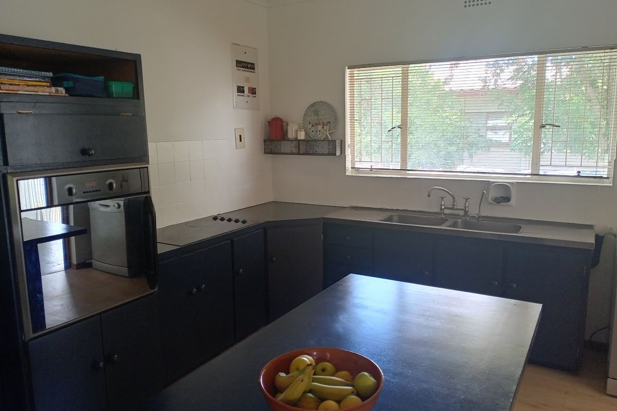 A functional kitchen featuring dark cabinetry, a built-in oven, a hob, and a double sink with a window view.