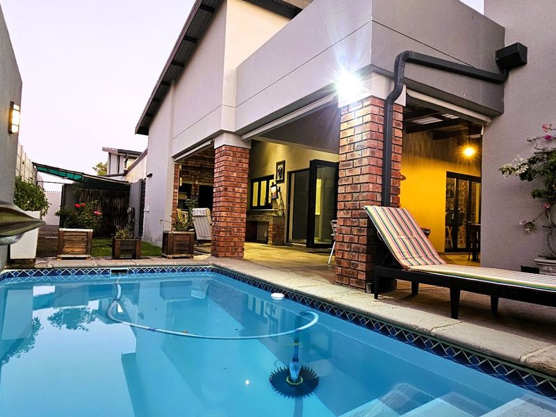 A well-maintained swimming pool area featuring a covered patio with brick pillars, providing a functional outdoor entertainment space.