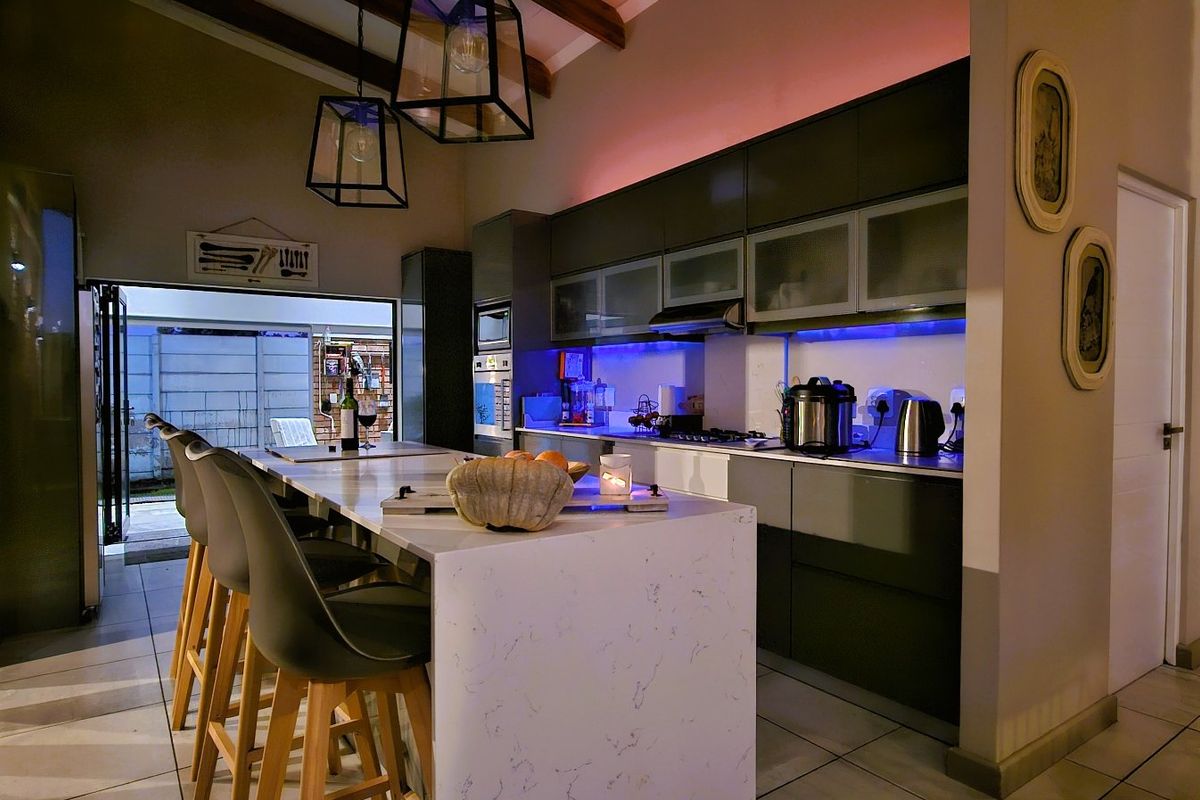 Modern kitchen featuring a stone-topped island, sleek cabinetry, built-in appliances, and exposed timber beams, creating a stylish and functional culinary space.