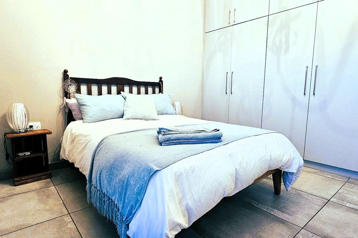 A well-maintained bedroom featuring neutral tiled flooring and extensive floor-to-ceiling built-in cupboards for ample storage.
