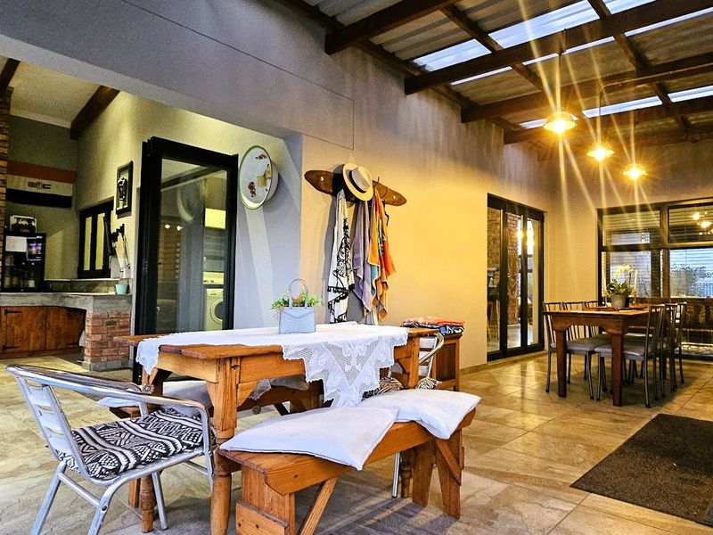 Spacious covered patio featuring a built-in brick fireplace, tiled flooring, and exposed timber beams, providing an ideal area for outdoor entertaining.