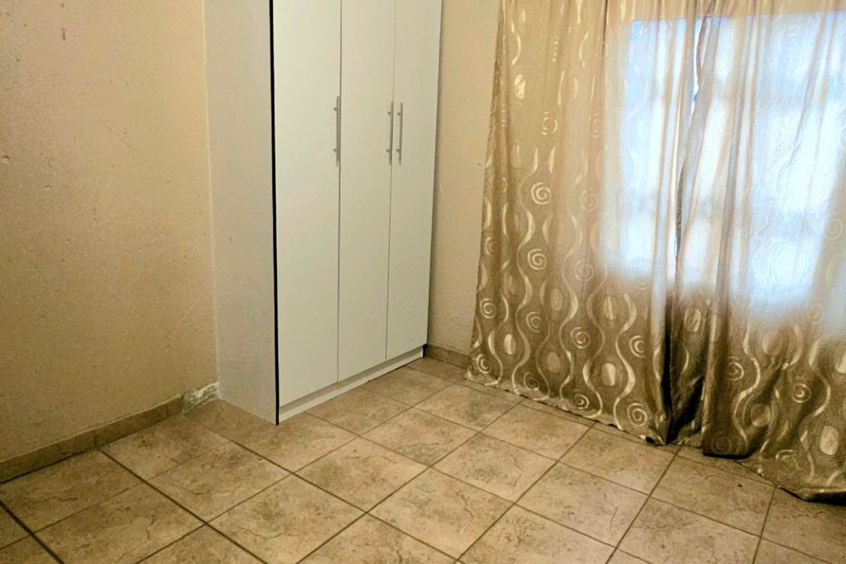 A simple bedroom featuring tiled flooring and a built-in wardrobe, offering a neutral space ready for personalization.