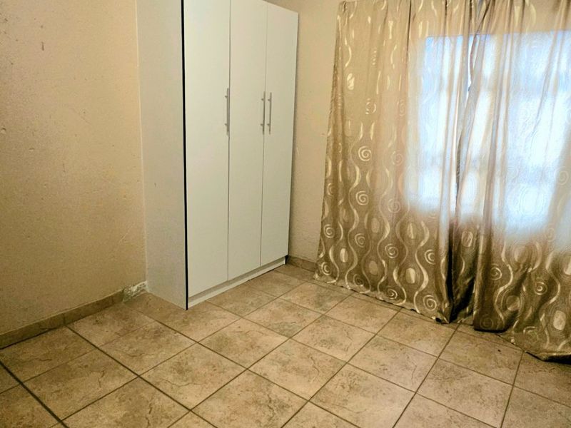 A simple bedroom featuring tiled flooring and a built-in wardrobe, offering a neutral space ready for personalization.