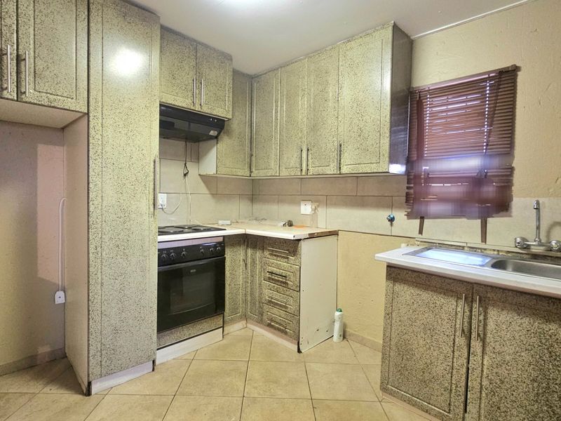 A functional kitchen featuring built-in cabinetry, an electric stove with extractor fan, and a double sink, offering a practical layout for renovation.
