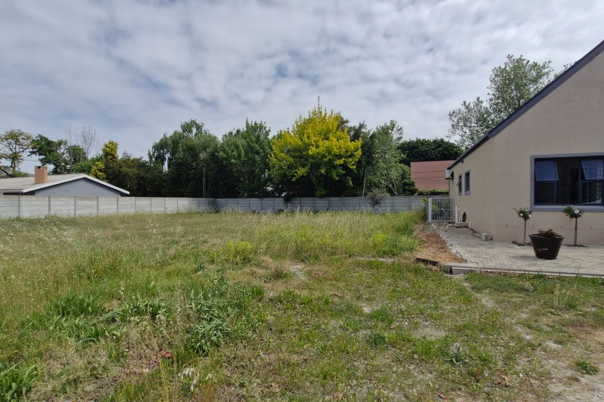 A spacious rear yard featuring a paved patio area and a precast concrete boundary wall, offering significant potential for landscaping and outdoor development.