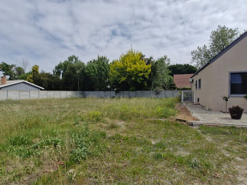 A spacious rear yard featuring a paved patio area and a precast concrete boundary wall, offering significant potential for landscaping and outdoor development.