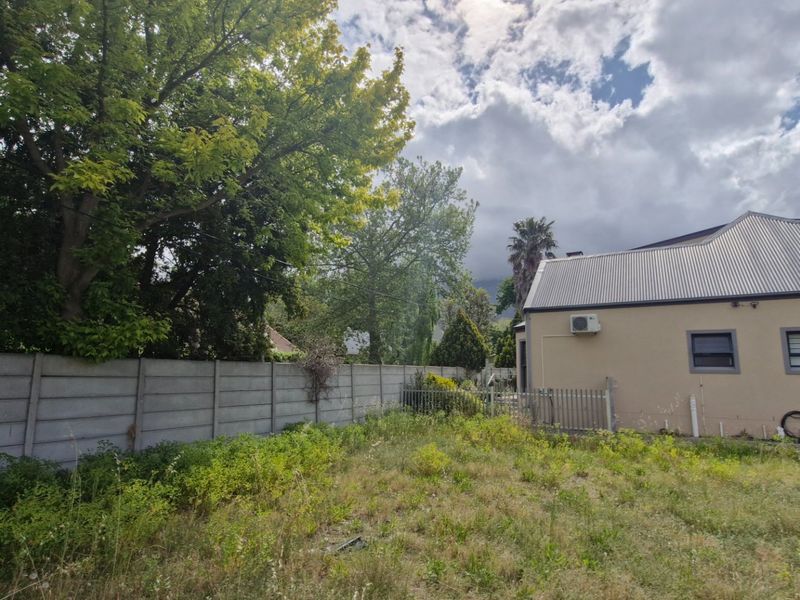 Rear view of the property showing a large, overgrown garden area, precast concrete boundary wall, and the rear elevation of the building.