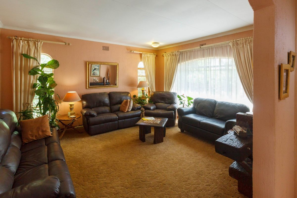 A spacious living room featuring large arched windows, textured walls, and carpeted flooring, offering a comfortable and traditional layout.