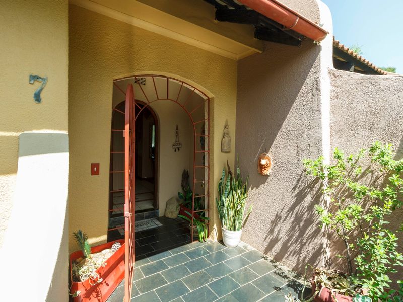 A covered entrance area featuring a security gate, tiled flooring, and textured exterior walls, providing a welcoming and secure access point to the home.