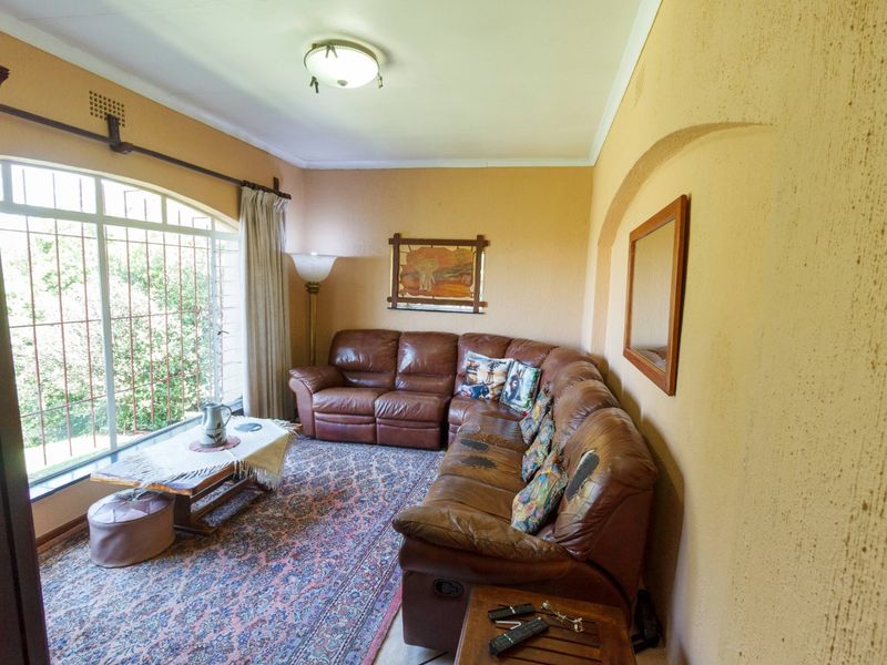 A living room featuring an arched window with security bars, textured walls, and a central ceiling light fixture.
