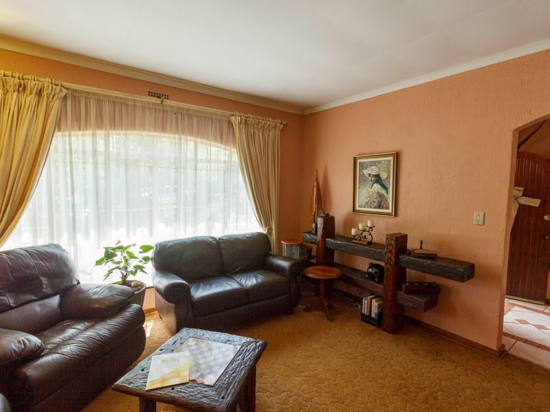 A living room featuring textured walls, carpet flooring, and an arched doorway leading to an adjacent tiled area.