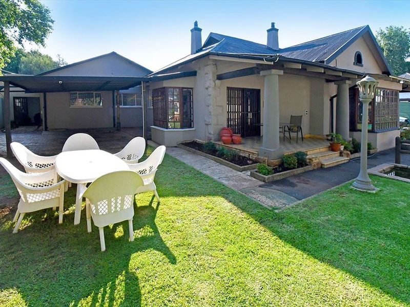Rear view of the property featuring a covered patio, attached carport, and a landscaped garden with a small pond.