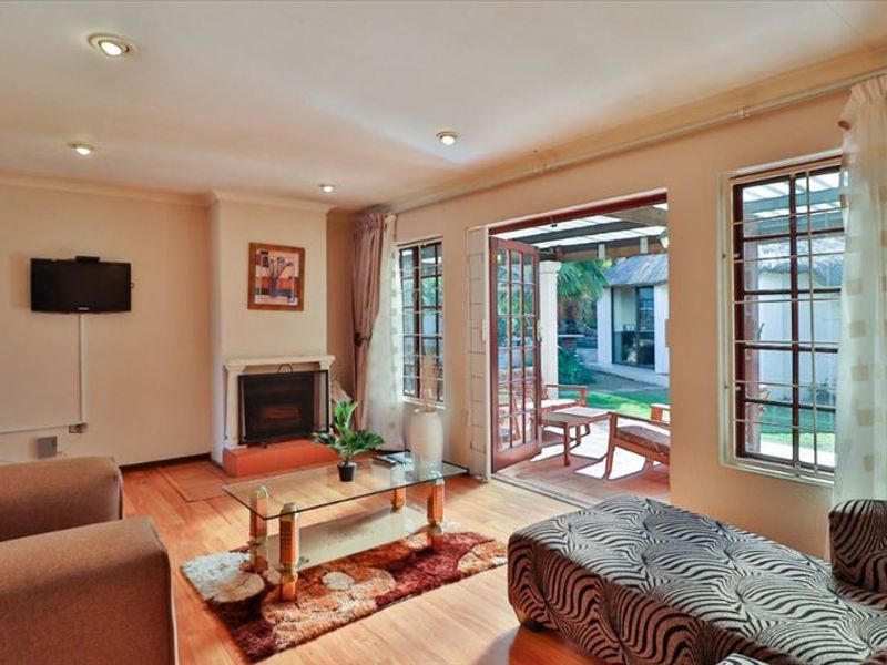 A comfortable living room featuring a fireplace, laminate flooring, and direct access to an outdoor patio area through double doors.