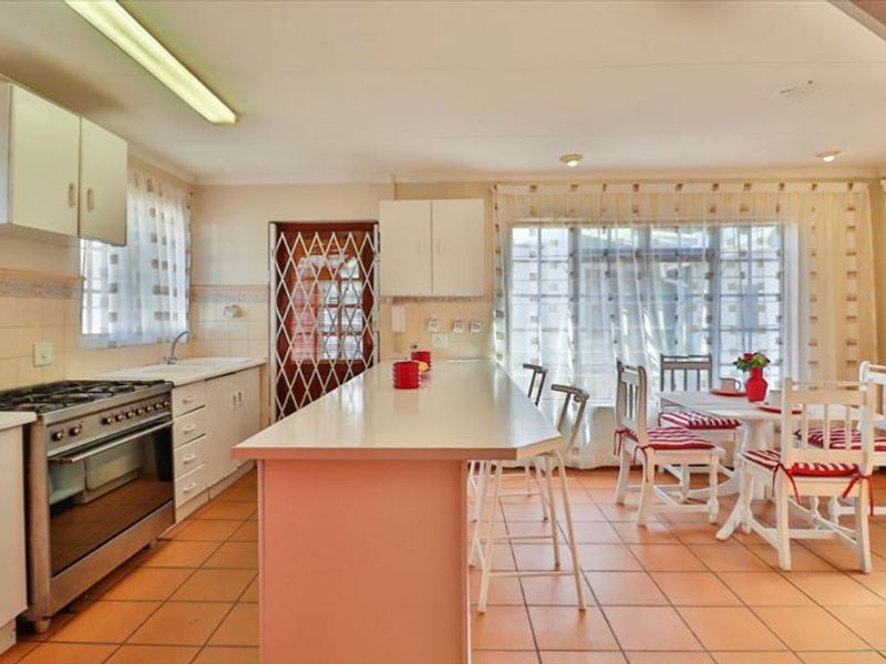 Open-plan kitchen and dining area featuring tiled flooring, built-in cabinetry, a central island, and a gas stove with oven.