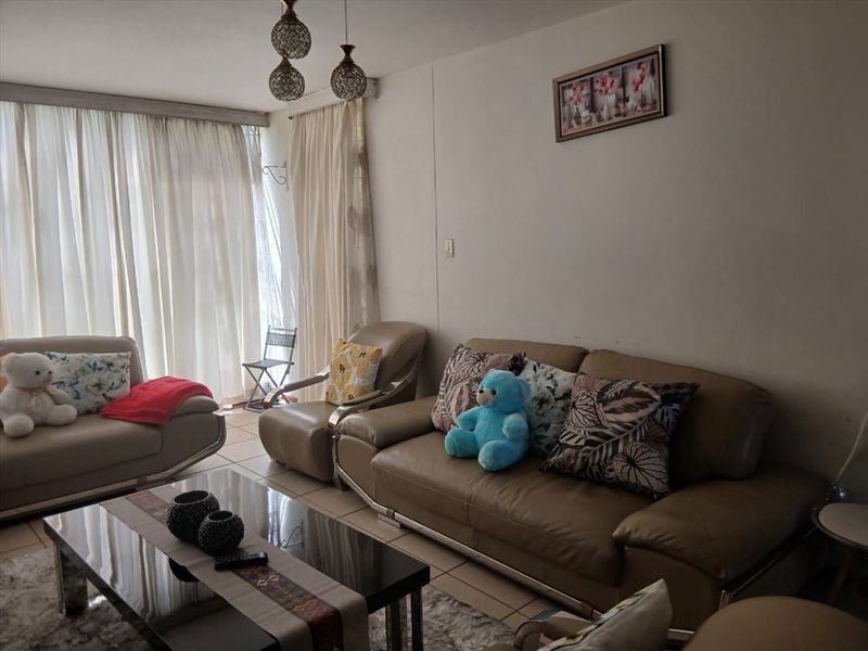 A comfortable living room featuring tiled flooring and a large sliding glass door that provides access to the outdoor area.