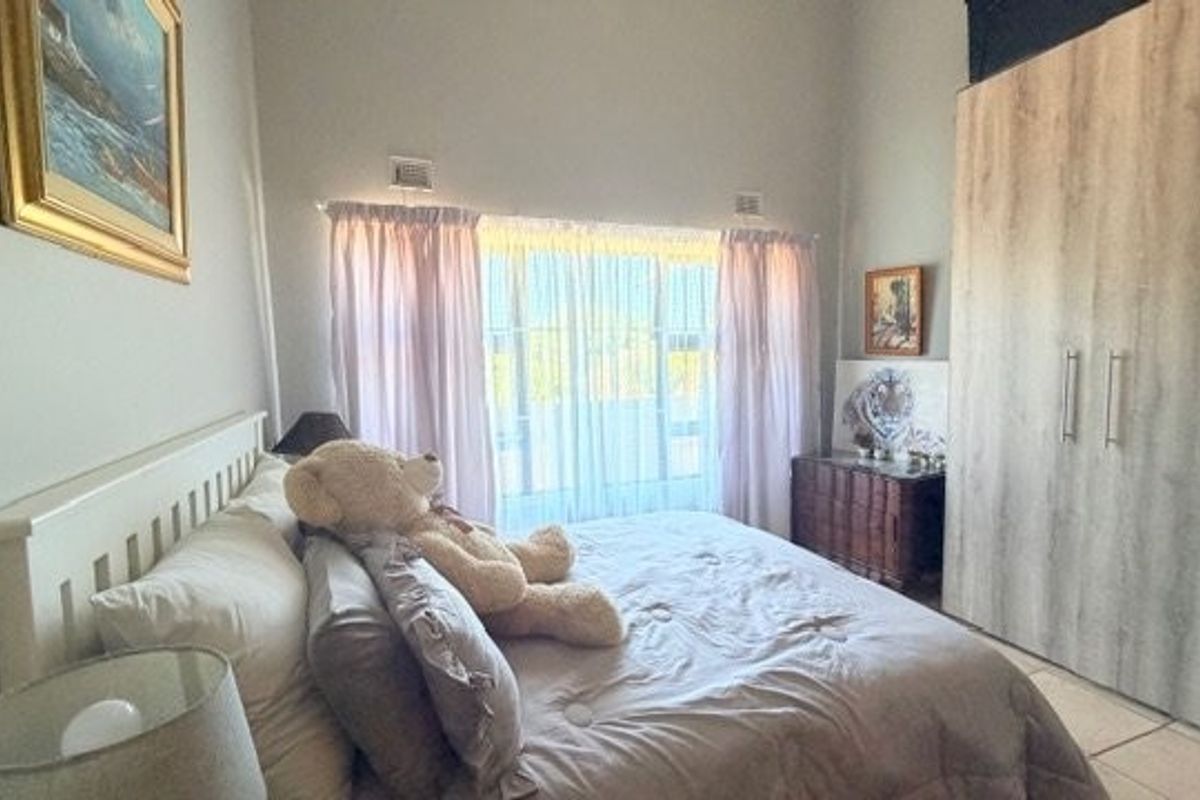 A well-lit bedroom featuring neutral walls, tiled flooring, and a large built-in wardrobe providing ample storage space.