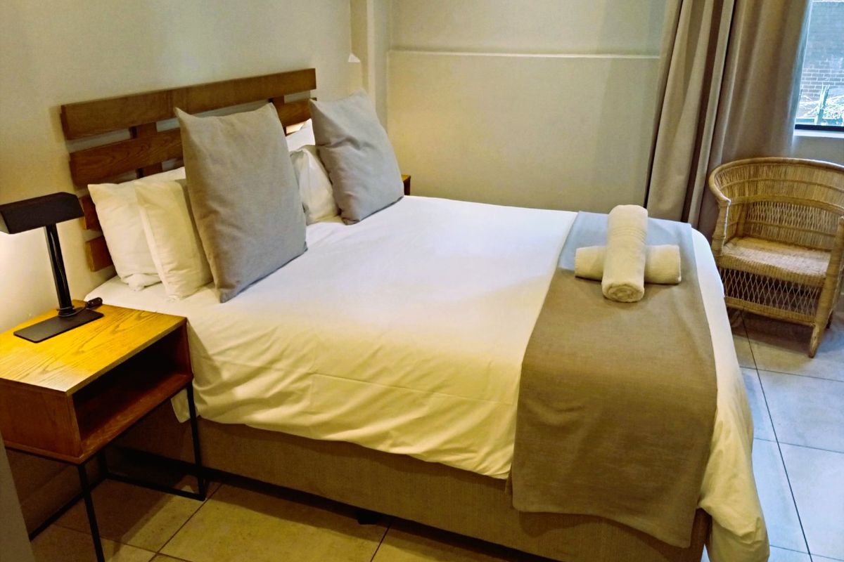 A well-maintained bedroom featuring neutral wall tones and tiled flooring, providing a comfortable and functional sleeping space.