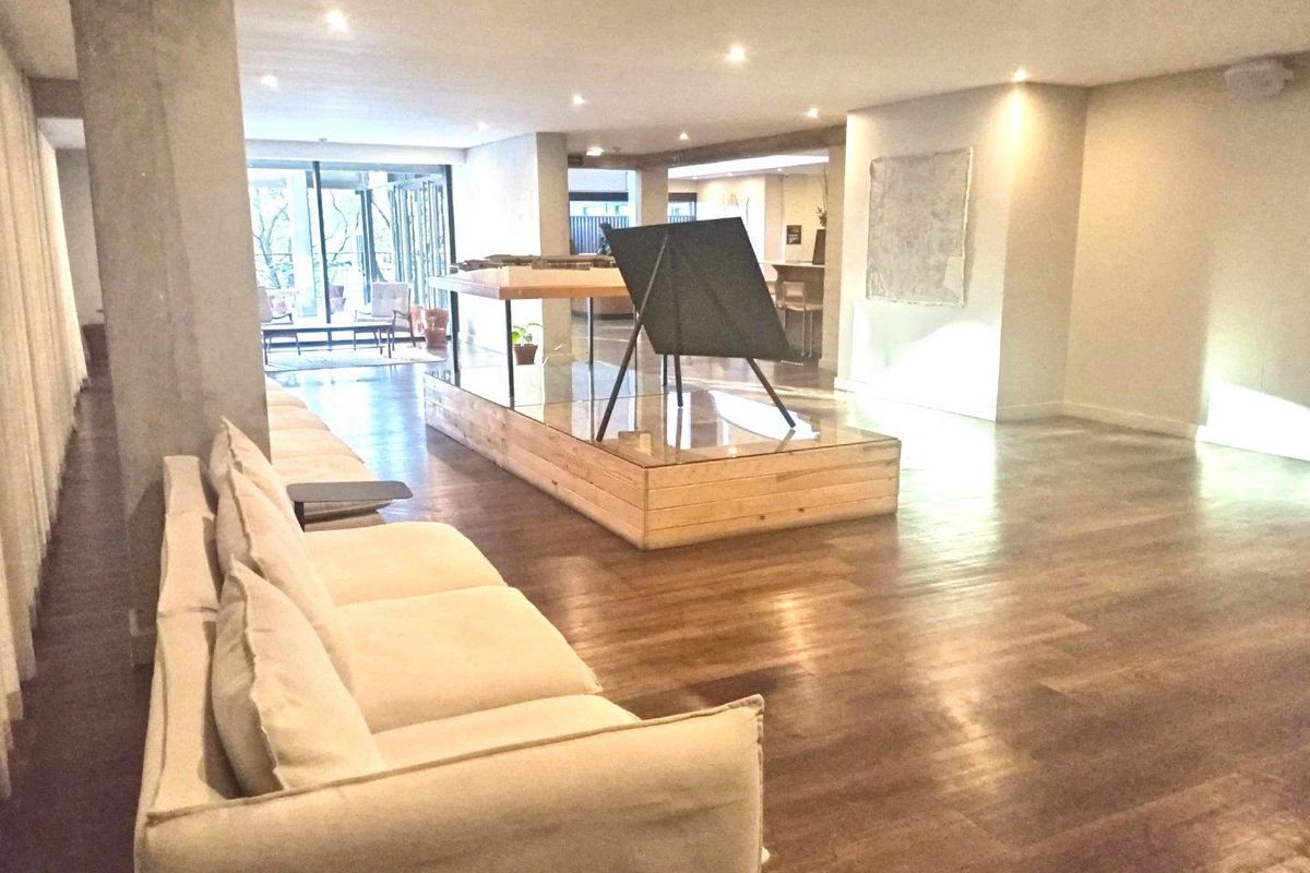 Spacious open-plan living area featuring hardwood flooring, recessed downlighting, and a prominent concrete structural pillar.