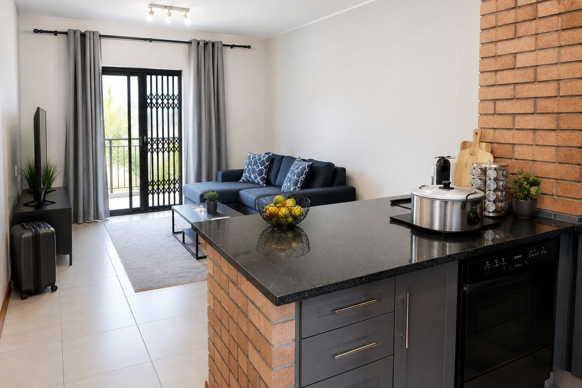 Open-plan living area featuring a modern kitchen with granite countertops, brick accents, and a sliding door leading to a balcony.