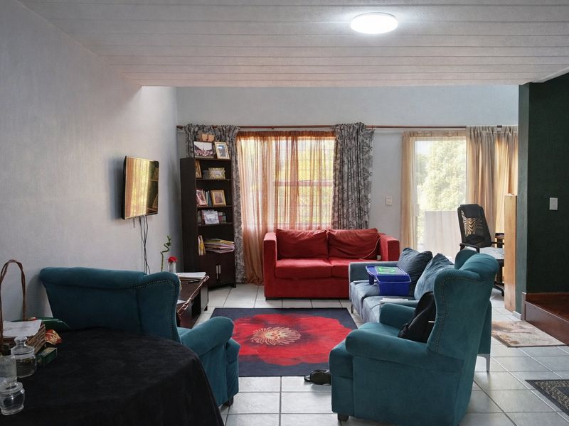 A spacious living room featuring tiled flooring, a ceiling light fixture, and a sliding glass door providing access to the exterior.