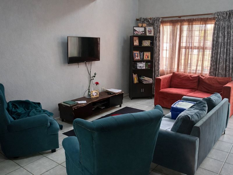A living room featuring tiled flooring and a window with a curtain rod, providing a functional space for relaxation.