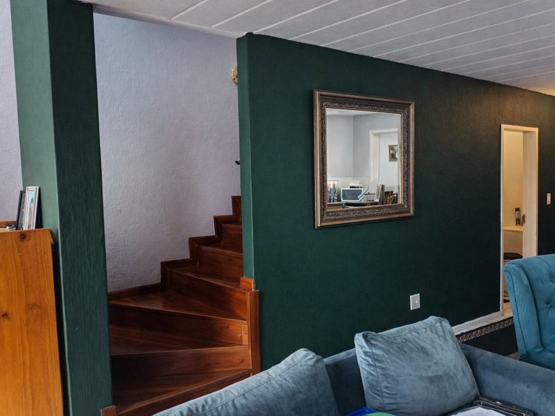 Living area featuring a dark green accent wall, a wooden staircase, and a tongue and groove ceiling.