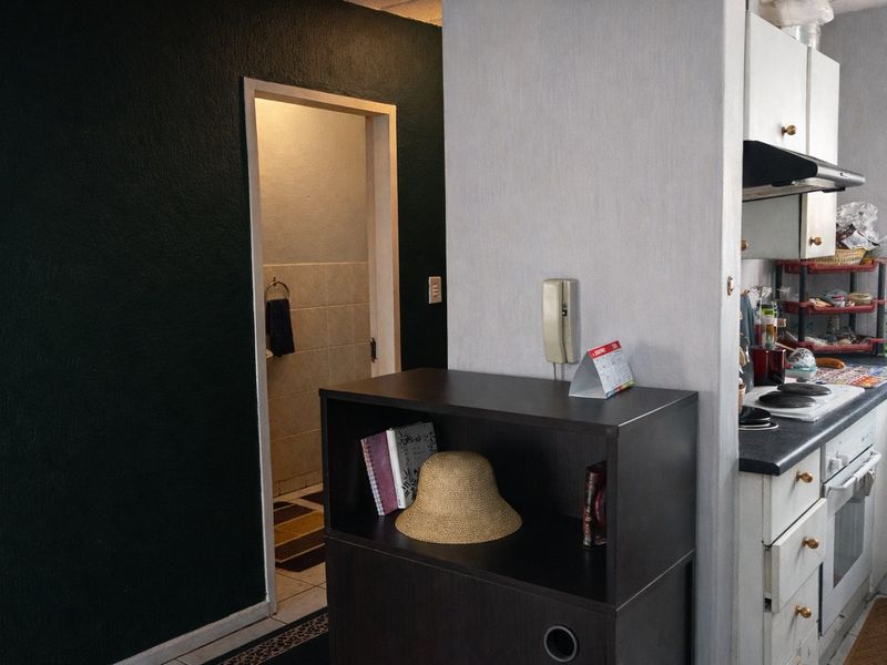 Open plan kitchen area featuring built-in cabinetry, electric hob, and oven, with an adjacent doorway leading to a tiled bathroom space.