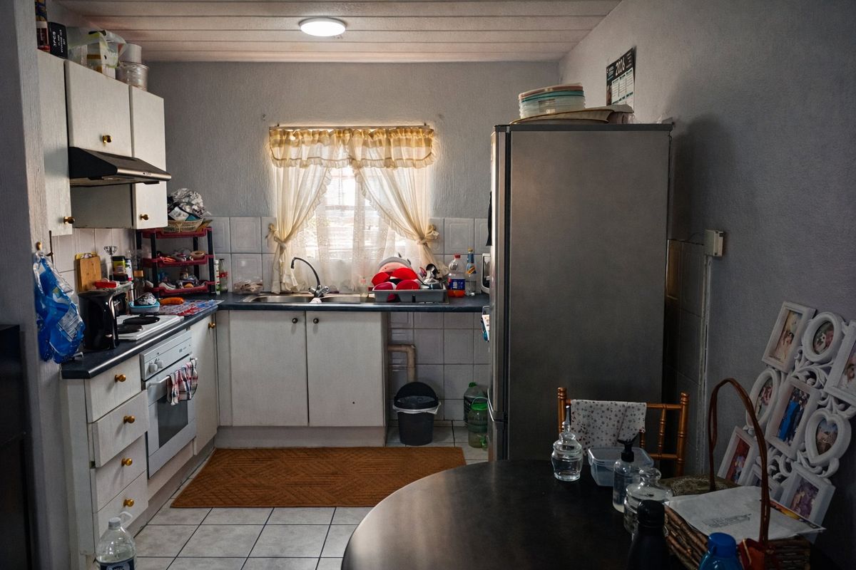 A functional kitchen featuring built-in cabinetry, a stainless steel sink, tiled backsplash, and integrated oven with extractor fan.
