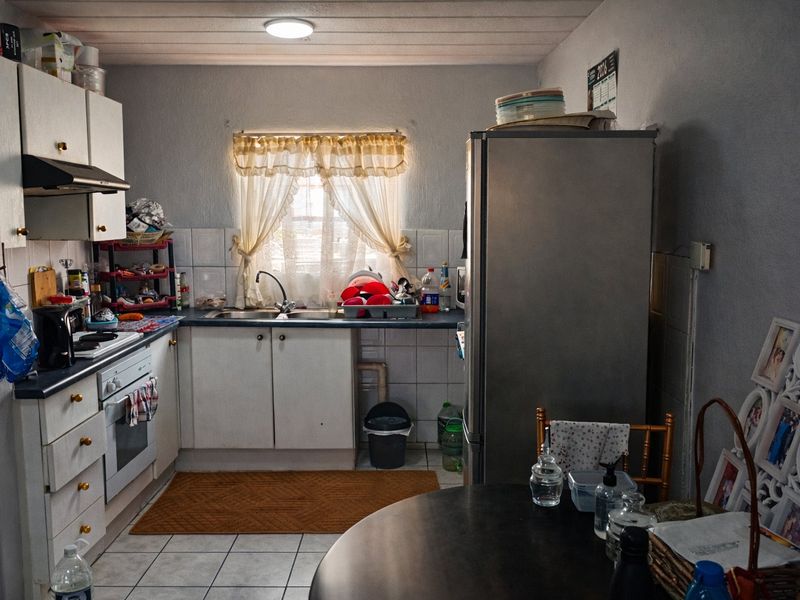 A functional kitchen featuring built-in cabinetry, a stainless steel sink, tiled backsplash, and integrated oven with extractor fan.
