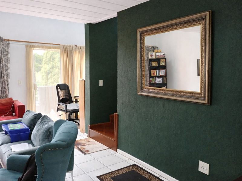 A living area featuring tiled flooring, a dark green accent wall, and a sliding glass door providing access to an outdoor space.