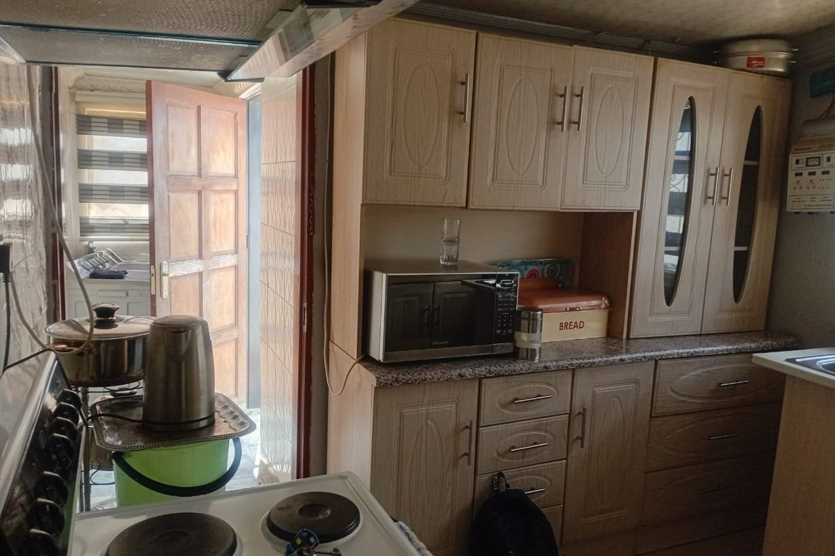 A functional kitchen featuring laminate cabinetry, granite-look countertops, and an integrated electric stove with an overhead extractor fan.