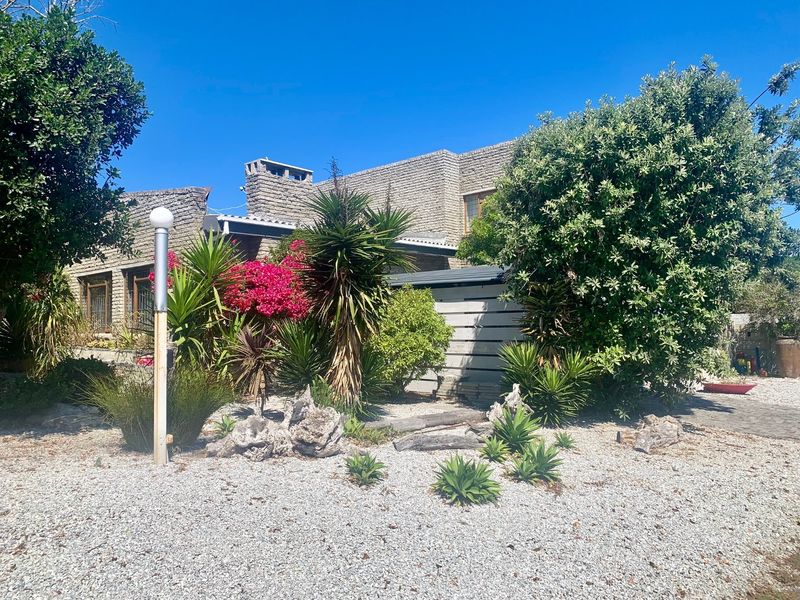 Front exterior view of a brick house featuring a chimney and established garden with gravel landscaping.