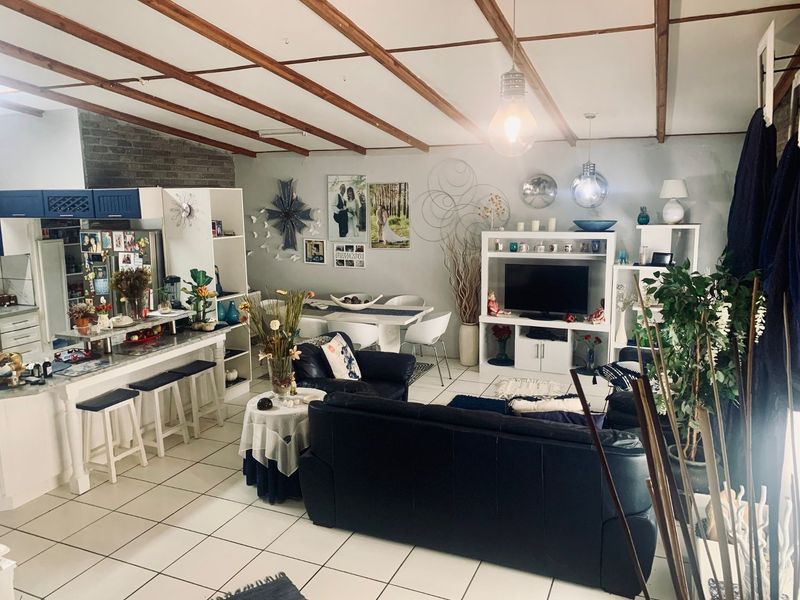 Spacious open-plan living area featuring exposed timber ceiling beams, tiled flooring, and a functional kitchen island, creating a versatile and connected living space.